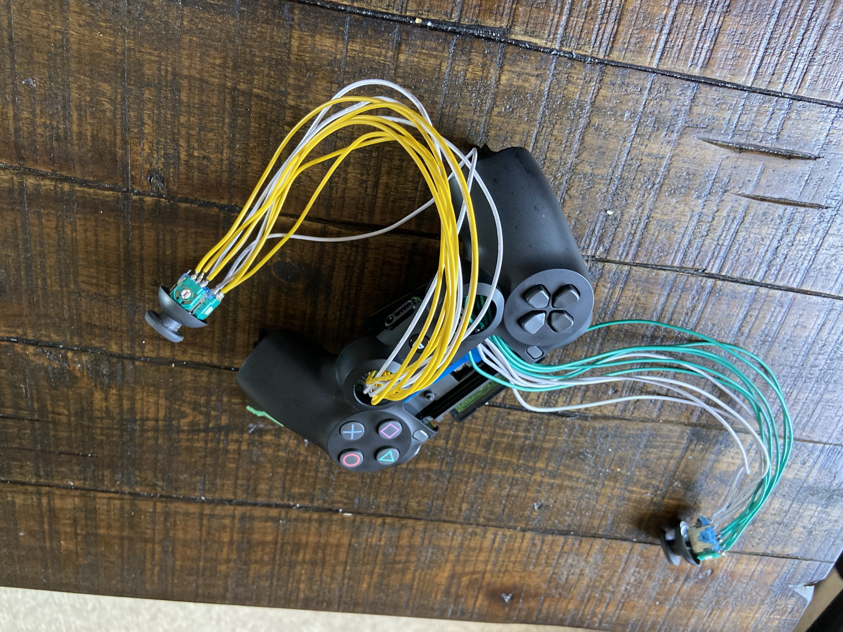 Open DualShock 4 with analog sticks on extended yellow and green wire harnesses