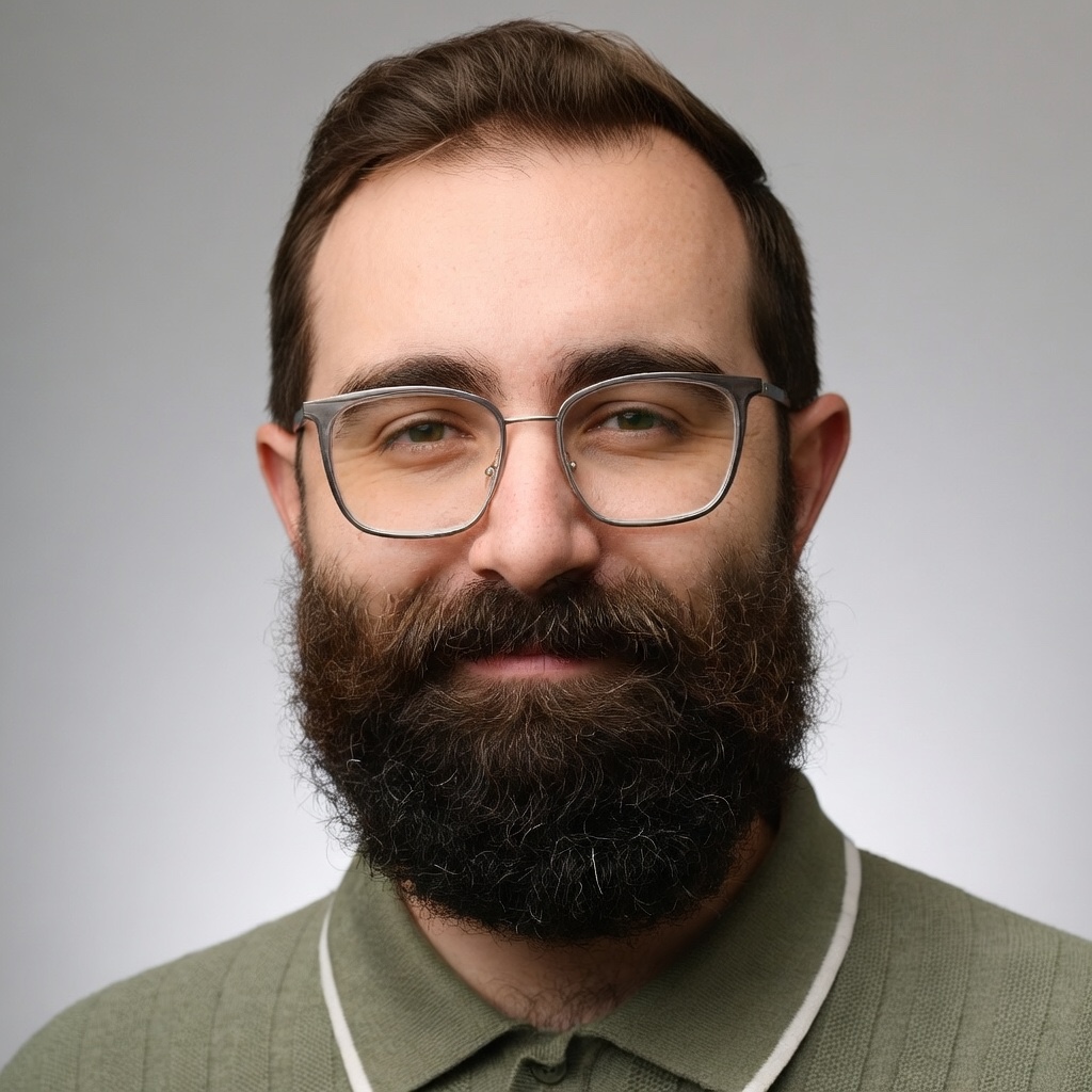 Headshot of James Alesi, bearded, wearing glasses and a green polo